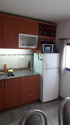 a kitchen with brown cabinets and a white refrigerator at Maganal in Villa Carlos Paz