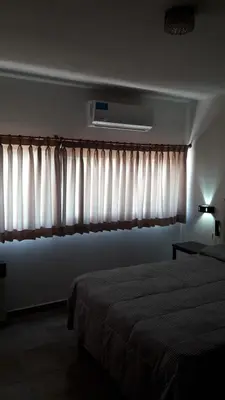 a bedroom with a bed and a window with curtains at Maganal in Villa Carlos Paz