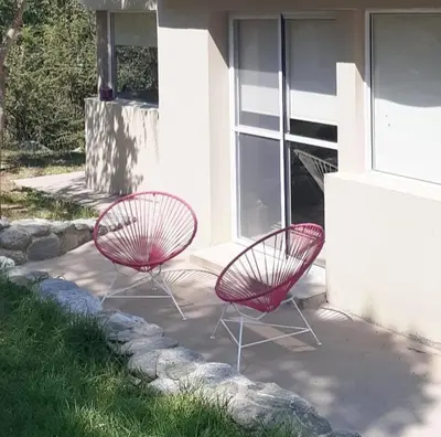 two red chairs sitting in front of a building at COSTA COM Cabañas in Merlo