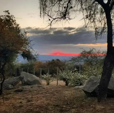 a sunset with a tree and rocks in a field at COSTA COM Cabañas in Merlo