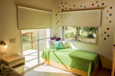 a bedroom with a green bed and a window at COSTA COM Cabañas in Merlo