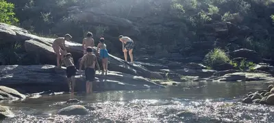 a group of people standing on rocks in a river at CABAÑAS CAMPO CHICO in Trapiche