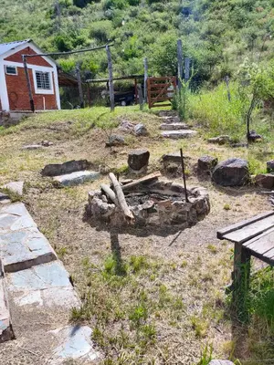 a fire pit in a field next to a house at CABAÑAS CAMPO CHICO in Trapiche