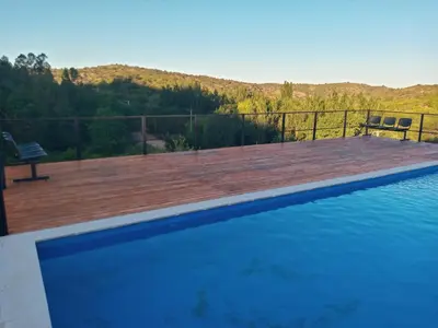 a swimming pool with a wooden deck and a bench at CABAÑAS CAMPO CHICO in Trapiche