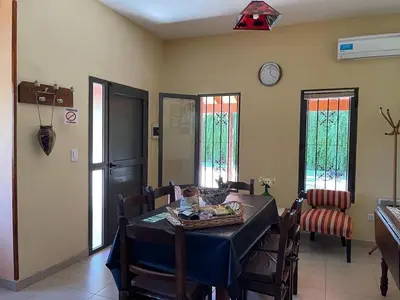 a dining room with a table and chairs and a clock at Cabañas Samarana in Carpintería
