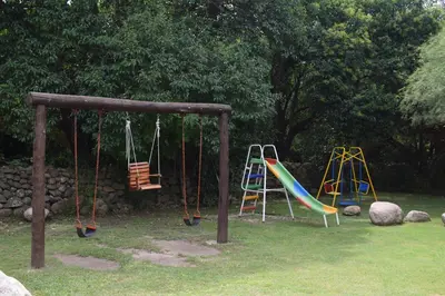 a playground with two swings and a slide at Cabañas La Curucucha in Nono