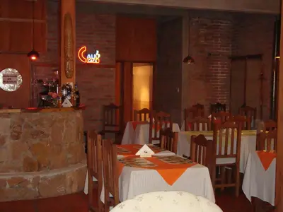a restaurant with tables and chairs and a neon sign at Principado Sierras Hotel in Mina Clavero