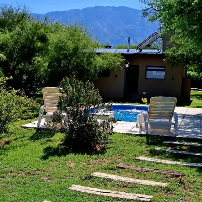 two chairs sitting in the grass near a swimming pool at Cabañas Altos de San Blas in San Javier
