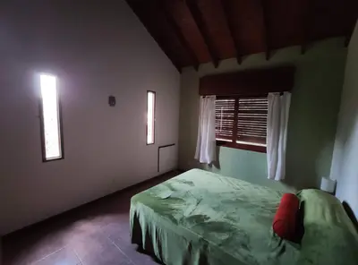 a bedroom with a green bed and two windows at Casa Etor in Merlo