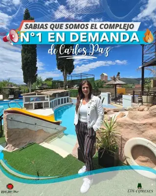 a woman standing in front of a pool at a theme park at Complejo Los Cipreses in Villa Carlos Paz