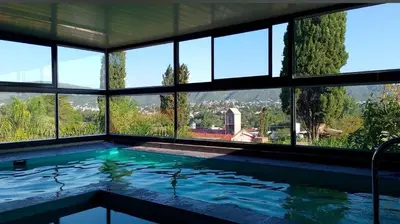 a large swimming pool in a house with windows at Complejo Los Cipreses in Villa Carlos Paz
