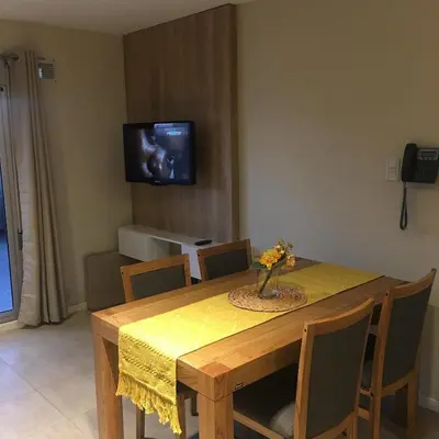 a dining room with a table and a tv on the wall at Apart Ribera, Rio Cuarto in Río Cuarto