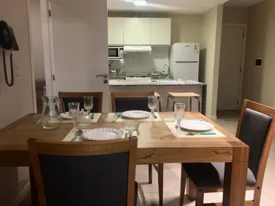 a wooden table with plates and glasses on it in a kitchen at Apart Ribera, Rio Cuarto in Río Cuarto