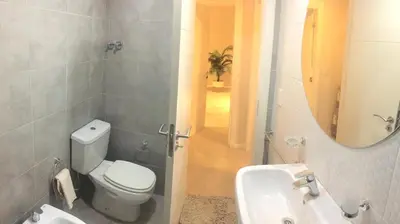 a bathroom with a toilet and a sink and a mirror at Apart Ribera, Rio Cuarto in Río Cuarto