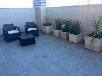 a patio with chairs and potted plants in a building at Apart Ribera, Rio Cuarto in Río Cuarto