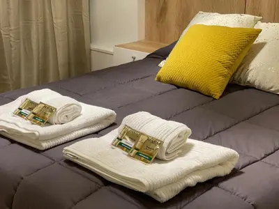 a bed with two towels and a yellow pillow at Apart Ribera, Rio Cuarto in Río Cuarto