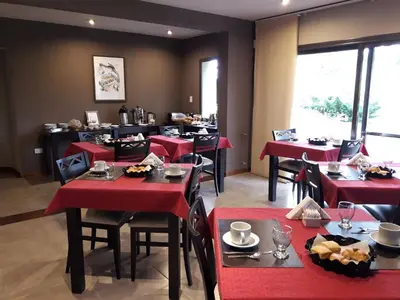 a restaurant with red tables and chairs in a room at Melodias Posada Boutique in Los Reartes