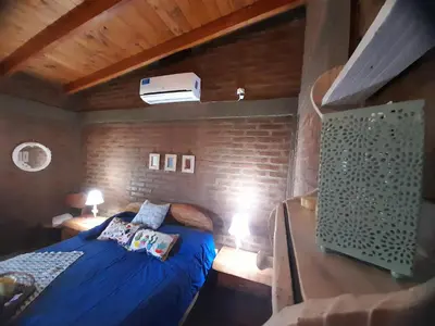 a bedroom with a blue bed and a brick wall at PIEDRALAGO CABAÑAS Y TURISMO in Villa Carlos Paz