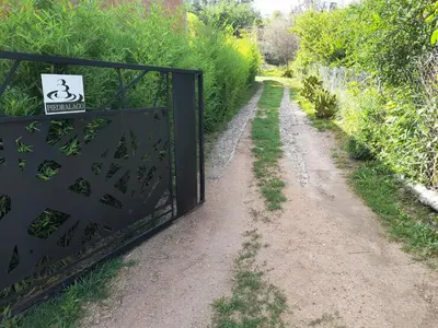 a gate on a dirt road with a sign on it at PIEDRALAGO CABAÑAS Y TURISMO in Villa Carlos Paz