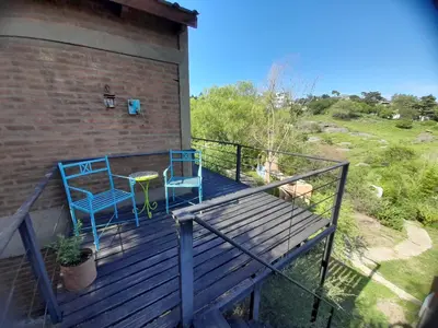 two blue chairs and a table on a deck at PIEDRALAGO CABAÑAS Y TURISMO in Villa Carlos Paz