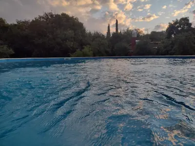 a large pool of water with trees in the background at El Manantial in La Población