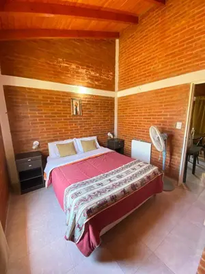 a bedroom with a large bed in a brick wall at Aiken Cabañas in Villa Cura Brochero