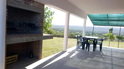 a table and chairs on a porch with a view at Aiken Cabañas in Villa Cura Brochero
