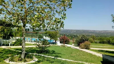 a garden with a tree and a swimming pool at Aiken Cabañas in Villa Cura Brochero