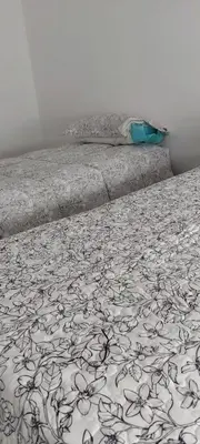 a bed with a black and white comforter on it at El canto de los pajaros in Villa Carlos Paz