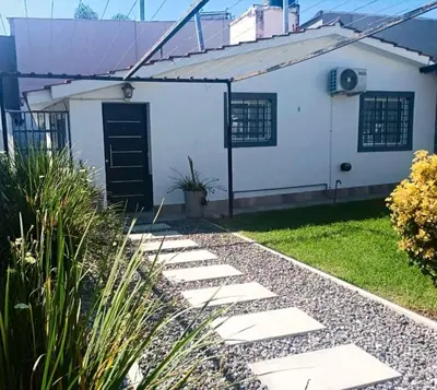 a white house with a black door and a walkway at Departamento zona centrica en Villa Carlos Paz in Villa Carlos Paz