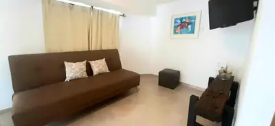 a living room with a brown couch and a chair at Departamento zona centrica en Villa Carlos Paz in Villa Carlos Paz