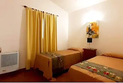 a room with two beds and a window with yellow curtains at Departamento zona centrica en Villa Carlos Paz in Villa Carlos Paz