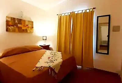 a bedroom with a bed and yellow curtains and a mirror at Departamento zona centrica en Villa Carlos Paz in Villa Carlos Paz