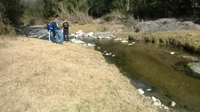 two people standing next to a river at Cabañas El Druida in Villa General Belgrano