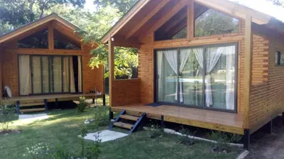 a wooden cabin with a large window in a yard at Cabañas El Druida in Villa General Belgrano