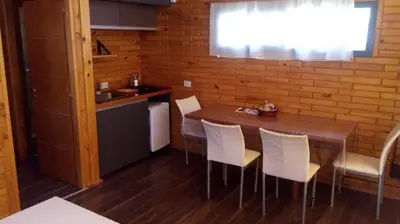 a kitchen with a wooden table and white chairs at Cabañas El Druida in Villa General Belgrano