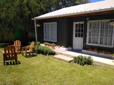 a house with two chairs and a table in the yard at Cabaña VGB. in Villa General Belgrano