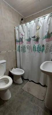 a bathroom with a toilet and a shower curtain at Cabaña VGB. in Villa General Belgrano