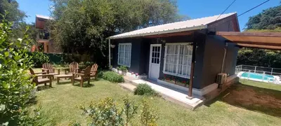 a blue house with a table and chairs in the yard at Cabaña VGB. in Villa General Belgrano