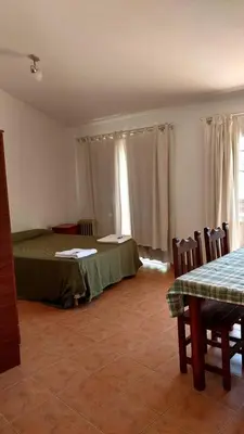 a bedroom with a bed and a table and chairs at Departamento Centro Calamuchita in Santa Rosa de Calamuchita