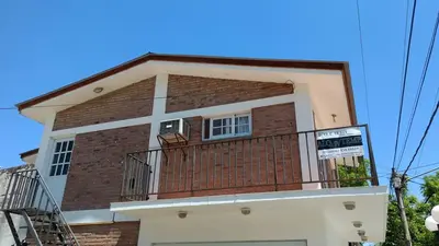 a house with a balcony and a blue sky at Departamento Centro Calamuchita in Santa Rosa de Calamuchita