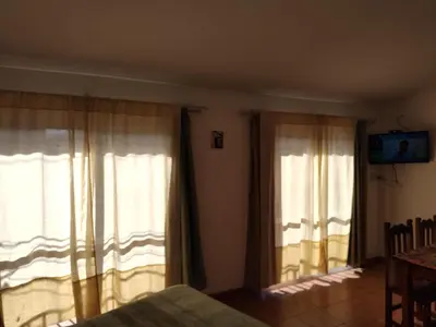 a bedroom with two windows with curtains and a table at Departamento Centro Calamuchita in Santa Rosa de Calamuchita