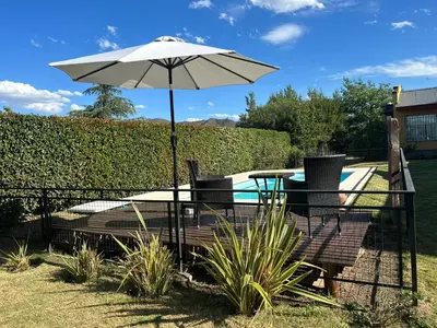 a patio with a table and an umbrella next to a pool at Sierras VGB Bertone in Villa General Belgrano