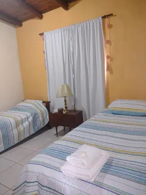 a bedroom with two beds and a table with a lamp at Valle de Fatima in Villa de Las Rosas
