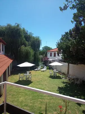 a yard with tables and chairs and umbrellas at Sauce Viejo in Mina Clavero