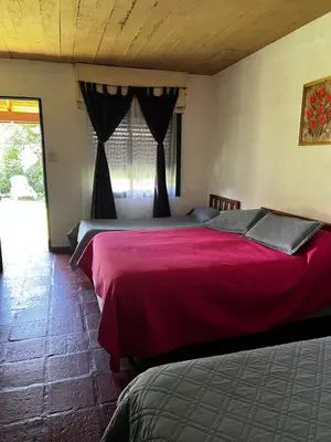 a bedroom with two beds with red sheets and a window at Sauce Viejo in Mina Clavero