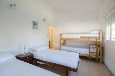 a room with three bunk beds and a window at Casa en Villa Carlos Paz con Pileta , Quincho y Jardín a Pasos del Centro in Villa Carlos Paz