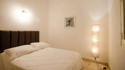 a bedroom with a white bed and a lamp at Casa en Villa Carlos Paz con Pileta , Quincho y Jardín a Pasos del Centro in Villa Carlos Paz