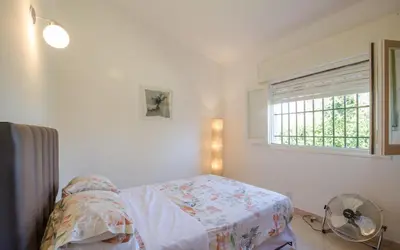 a bedroom with a bed and a window and a fan at Casa en Villa Carlos Paz con Pileta , Quincho y Jardín a Pasos del Centro in Villa Carlos Paz
