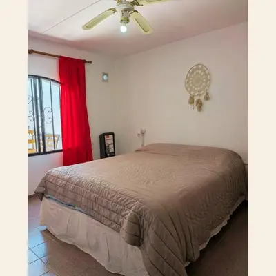 a bedroom with a bed with a red curtain at Alojamientos Bolivar in Mina Clavero